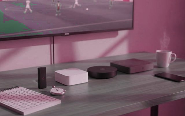 Five streaming devices beside a scoring notepad and a stopwatch, in front of a TV showing a soccer match