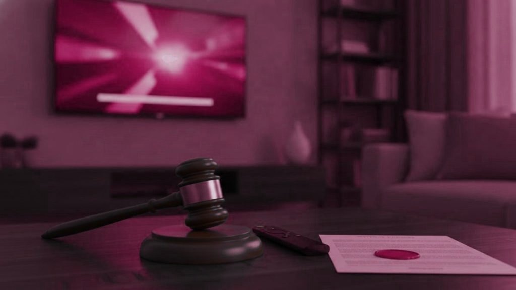 A gavel, a streaming remote and a sealed legal document on a coffee table before a switched-on television